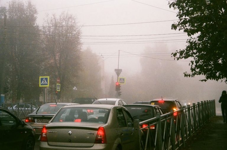Пешеходы идут вдоль дороги в дымке